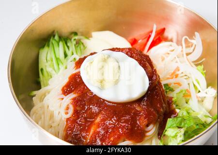 Asian noodles, salad, kimchi sauce, and a hard boiled egg at a Korean restaurant.  White Background. Stock Photo