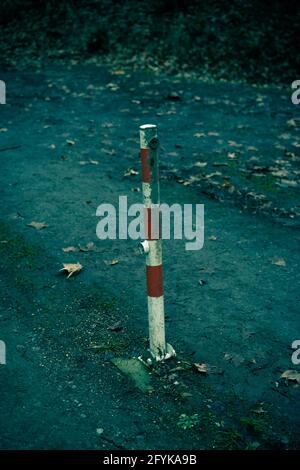 Vertical shot of a metal traffic pole with red lines on a grungy road at night Stock Photo