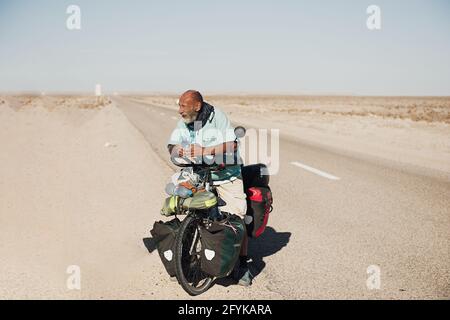 Nouadhibou, Mauritania, JANUARY 18, 2020: Man on bicycle cycling on Mauritania desert Stock Photo