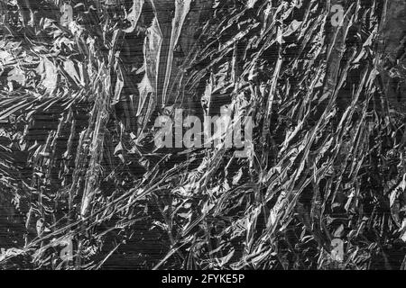 Black glued crumpled shiny grunge plastic. Wrinkled polyethylene film. Abstract background Stock Photo