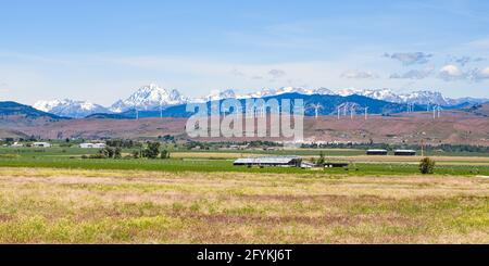 The Kittitas Valley in late Spring as the Cascade Mountains rise above the wind farm in the foothills.  The agriculture land begins it annual cycle Stock Photo
