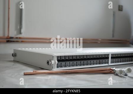 Central heating pipes and radiator on the floor at construction site in apartment house or building in day Stock Photo