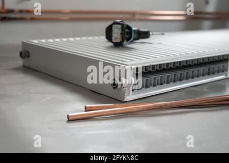 Central heating pipes electric screwdriver and radiator on the floor at construction site in apartment house or building in day with copy space Stock Photo