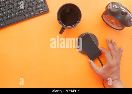 charging Smartphone using Wireless Charging Pad on orange background  Stock Photo