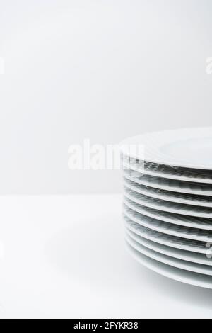 Set of washed stacked white dishes on a white table. Stock Photo