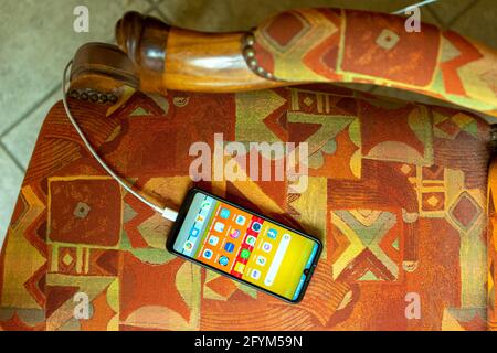 MILAN, ITALY - May 26, 2021: A phone is charging with the screen on showing many apps Stock Photo