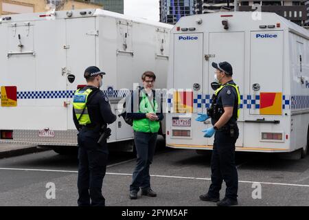 Melbourne, Australia 29 May 2021, police question a protest medic during a planned 'Millions March' rally at Flagstaff Gardens, that had been canceled by organisers due to the snap lockdown. Hardcore anti-lockdown and anti-vaccination protesters still attend the park and rallied against the government. Credit: Michael Currie/Alamy Live News Stock Photo