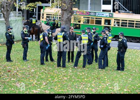 Melbourne, Australia 29 May 2021, A protest leader 'Harrison' is escorted by police during a planned 'Millions March' rally at Flagstaff Gardens, that had been canceled by organisers due to the snap lockdown. Hardcore anti-lockdown and anti-vaccination protesters still attend the park and rallied against the government. Credit: Michael Currie/Alamy Live News Stock Photo