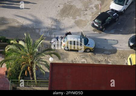 ALICANTE, SPAIN, APRIL 28 2021: two men pushing damaged car in the city of Alicante, in the Valencian Community, Spain. view Stock Photo