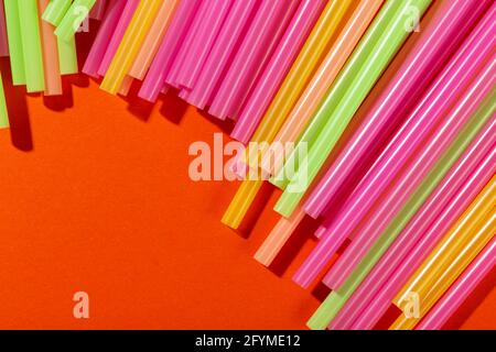 Colored tubules for juice and cocktails on orange background. Cocktail parties. Space for text. Stock Photo