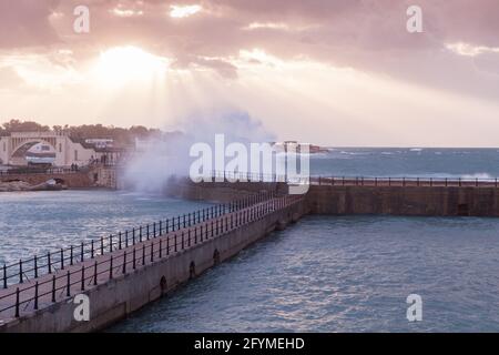 Coastal landscape with breakwater and splashing waves under dramatic evening sky. Alexandria, Egypt Stock Photo