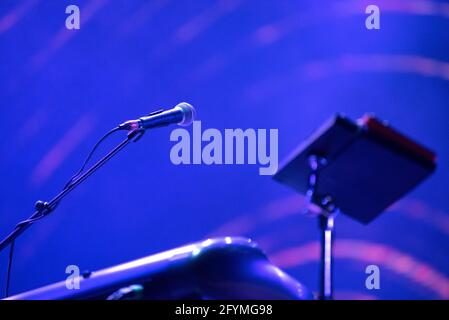 Microphone and music stand in blue stage lights at live concert Stock Photo