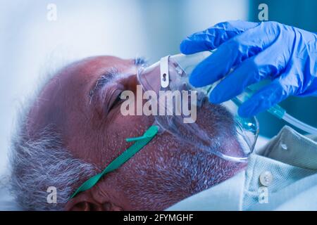 Close up shot, Doctor helping by adjusting ventilation oxygen mask to covid infected difficulty in breathing or breathlessness to patient at hospital Stock Photo