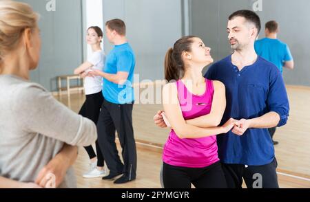 Cheerful adults learning to dance kizomba with partners in dancing group class Stock Photo