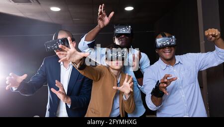 Cheerful nice friends playing  video games using virtual reality glasses Stock Photo