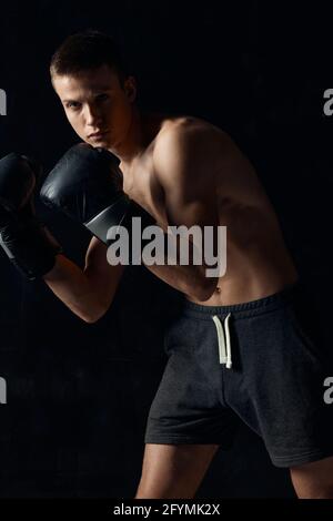 bodybuilder wearing boxing gloves black background cropped view sport  Stock Photo