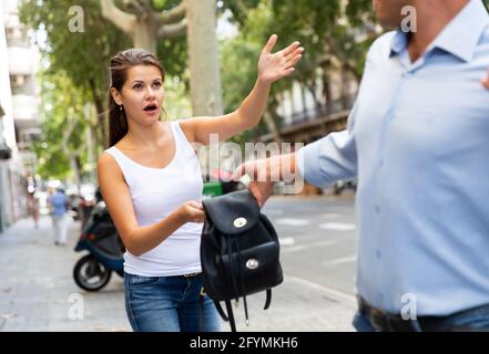 Bandit man is stole the handbag from emotional female on the street Stock Photo