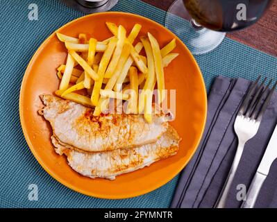 Roasted pork loin Lomo de cerdo con patata with potatoes fries on a ceramic plate cooked in a cafe Stock Photo