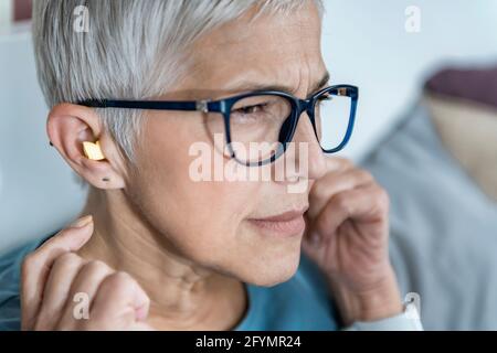 Mature woman using earplugs for sleeping Stock Photo