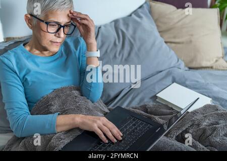 Woman using laptop computer in bed Stock Photo