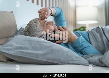 Woman using smartphone in bed Stock Photo