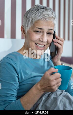 Woman using smartphone in bed Stock Photo