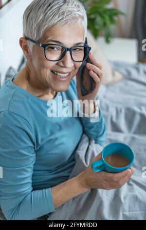 Woman using smartphone in bed Stock Photo
