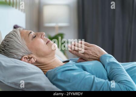 Woman lying in bed meditating Stock Photo