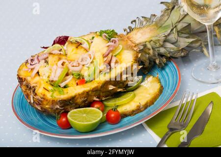 Salad with calamari, pineapple and lime served in pineapple shell with dressing from pineapple juice, olive oil, lemon and chili pepper Stock Photo