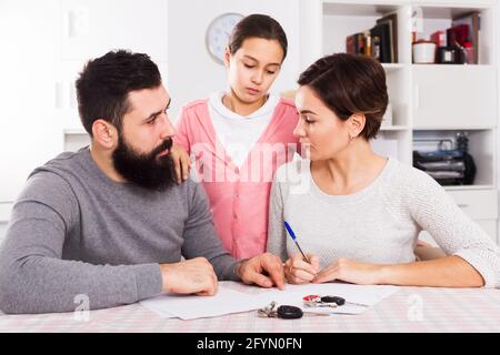 Young parents signing papers for divorce while their daughter at home Stock Photo