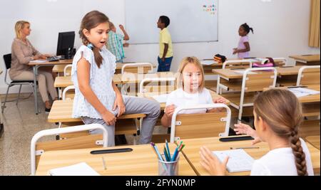 Cheerful preteen classmates talking to each other at recess between lessons in primary school Stock Photo