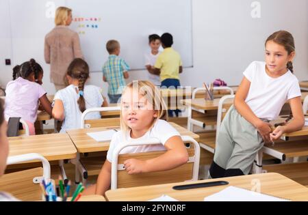Cheerful preteen classmates talking to each other at recess between lessons in primary school Stock Photo