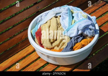 White bowl with colorful laundry on a wooden background outdoor Stock Photo