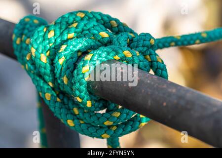 Green fishing nylon rope for mooring boats wrapped around a metal fence Stock Photo