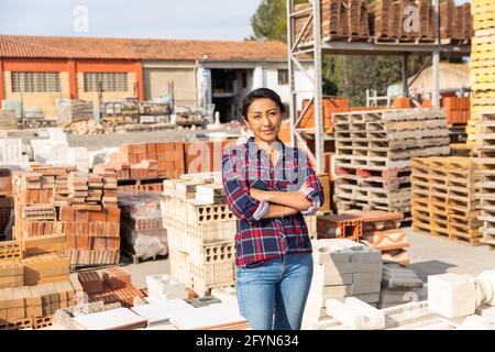 Smiling hispanic woman worker posing at building materials warehouse Stock Photo