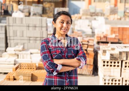 Smiling hispanic woman worker posing at building materials warehouse Stock Photo