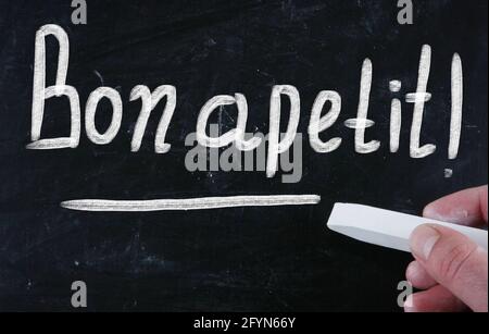 Closeup shot of a white text 'Bon apetit!' on a black surface Stock Photo