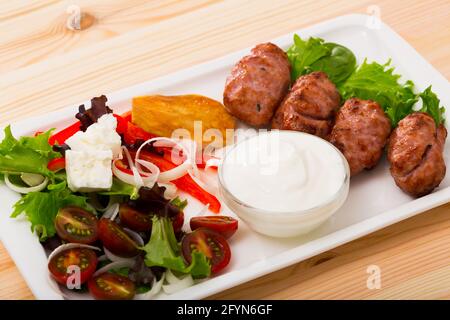 Dish of Bulgarian cuisine Kebapche - grilled meat sausages served with green salad and young cheese Stock Photo