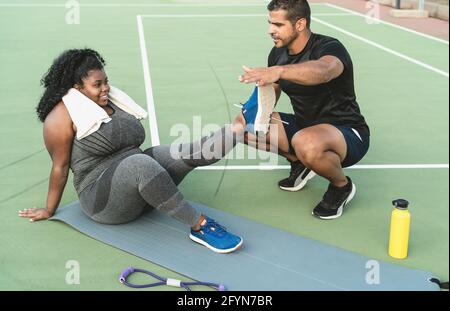 Personal trainer working with curvy woman explaining her the exercises routine - Sporty people lifestyle concept Stock Photo