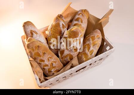 Freshly baked sourdough bread, baguette in white wooden basket, top view Stock Photo