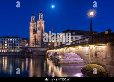 Munsterbrucke and Grossmunster church reflecting in the blue hour in river Limmat, Zurich, Switzerland Stock Photo