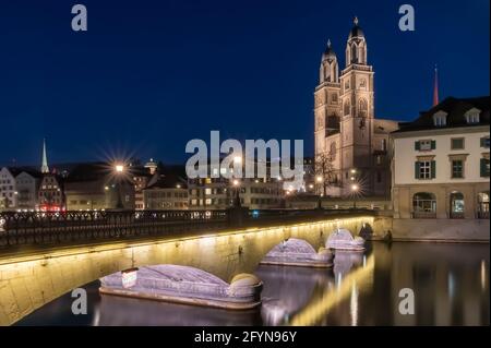 Munsterbrucke and Grossmunster church reflecting in the blue hour in river Limmat, Zurich, Switzerland Stock Photo