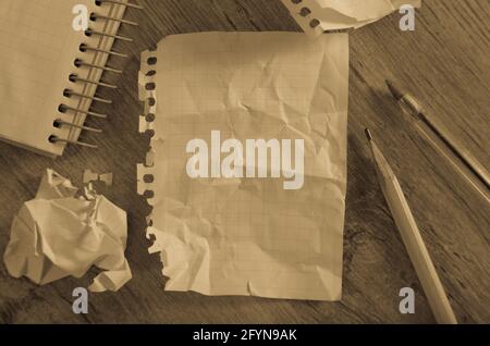 Crumpled empty pages and notebook lying on wooden surface Stock Photo