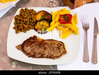 Well done beef with potatoes fries and grilled vegetables in a pub Stock Photo