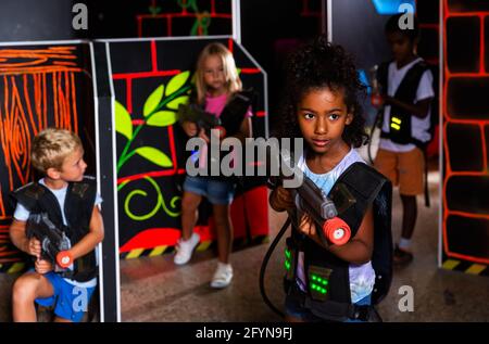Portrait of african tweenager girl with laser gun having fun on dark lasertag arena Stock Photo