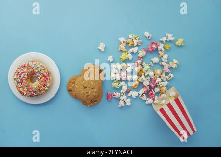 stack of cookies , donuts and popcorn on blue background  Stock Photo