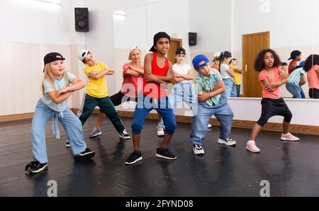 Group of happy tweens with female teacher practicing hip hop in modern dance studio Stock Photo