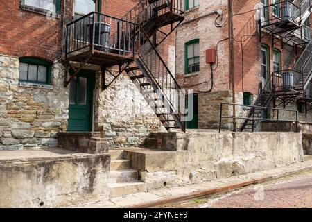 Backdrop of fire escapes, stairs, walls, railings, windows, doors, and walls on the rear of an old brick apartment building, horizontal aspect Stock Photo