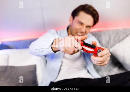 Blurred handsome male stay home quarantine time, exciting from console games.Excited young man playing video games, playstation football match,racing Stock Photo