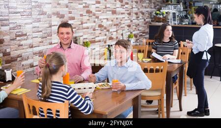 Smiling family with teenagers having lunch in cozy cafe Stock Photo